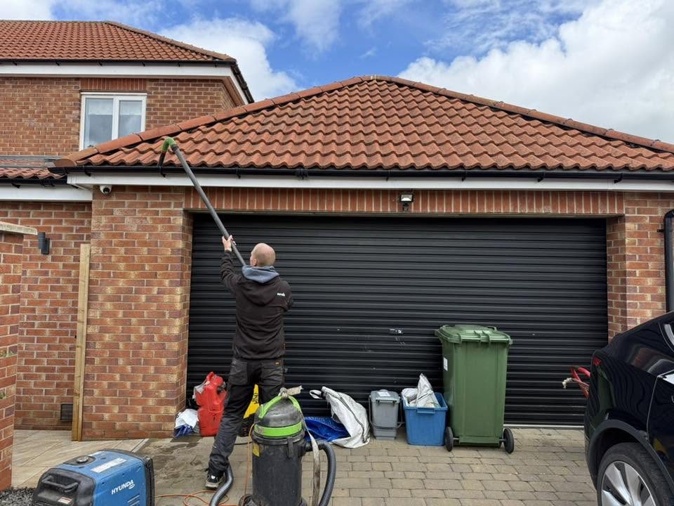 IGM operative vacuuming moss and debris from a garage roofline in Ingleby Barwick